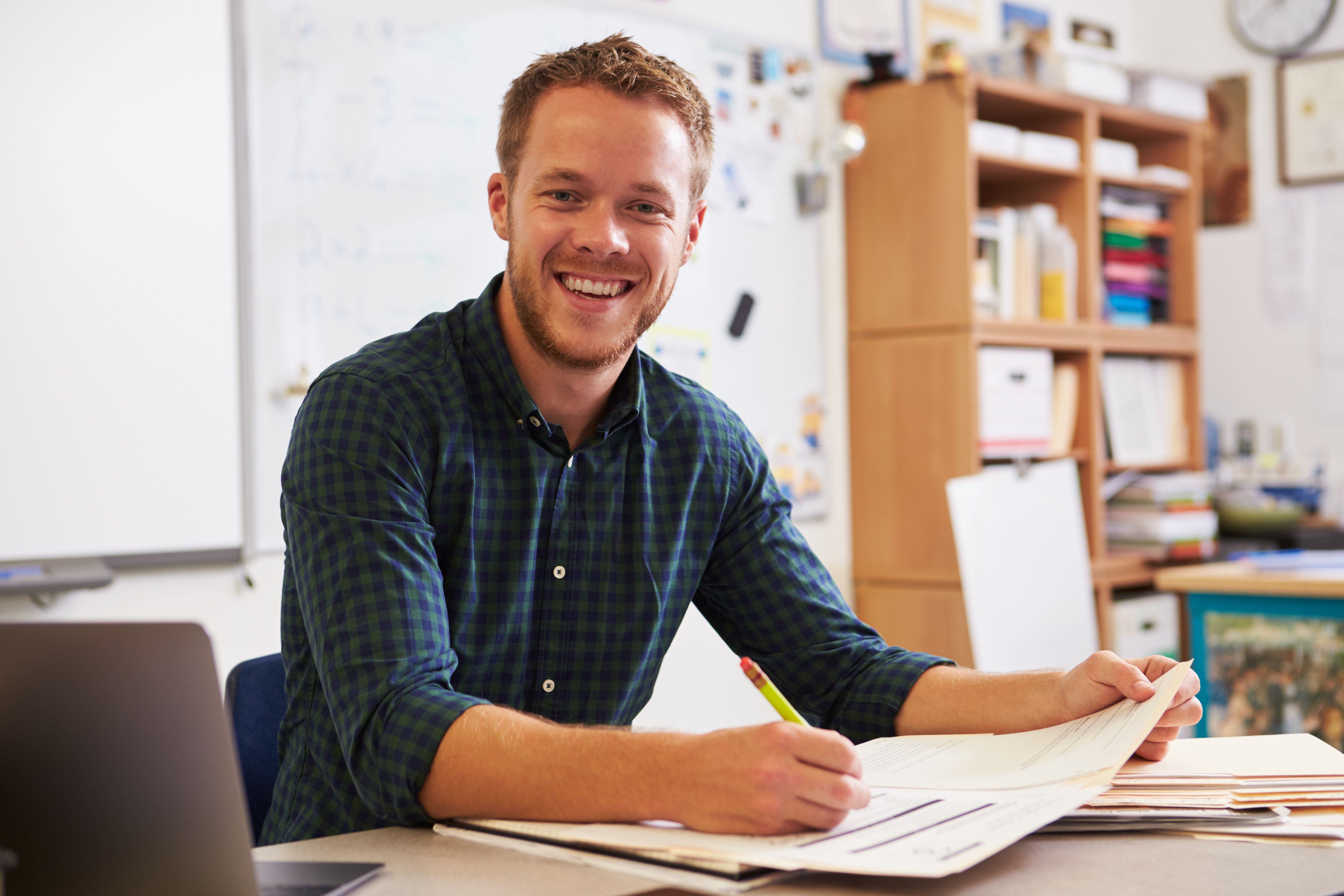 teacher-smiling-at-camera-over-marking
