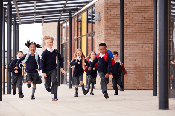 Seven primary school aged children running to school. 